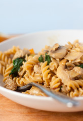 Sausage and mushroom pasta made with wholewheat fusilli in a white bowl