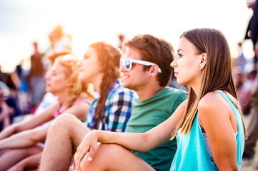 Teenagers at summer music festival, sitting on the ground