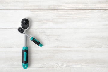 Different-sized ratchet wrenches on wooden background with copy space