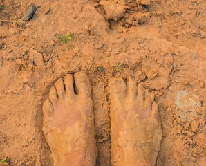 Muddy feet, standing on the sandy ground.
