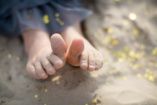 Girl sitting on beach, focus on barefeet