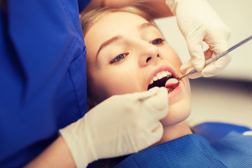 female dentist checking patient girl teeth