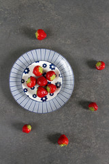 Strawberries blue and white plate, gray background.