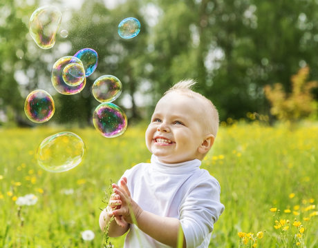 Little boy is happy multi-colored soap bubbles