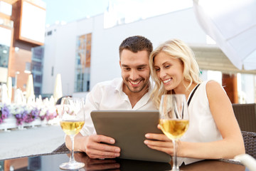 happy couple with tablet pc at restaurant terrace