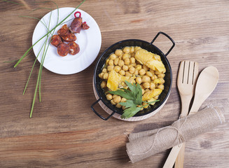Close-up of nutritious chickpeas with codfish and sausage on plate.Fork and spoon.From above.