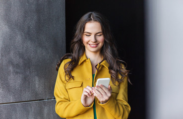 smiling young woman or girl texting on smartphone