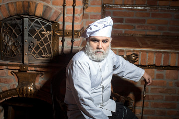 Senior cook sits at oven
