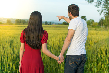 Fototapeta na wymiar Couple holding hands in a wheat field