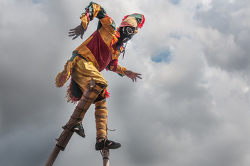 Man in jester costume balancing on stilts
