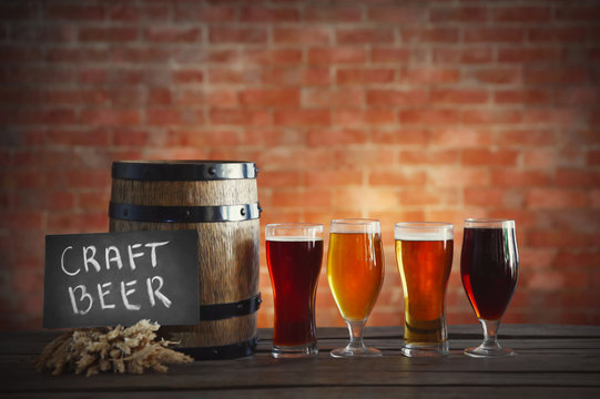 Glasses with different sorts of craft beer, wooden barrel and barley. Retro stylization
