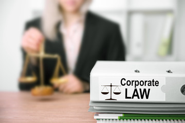 Young female judge working in her office. Folder with label Corporate Law on foreground