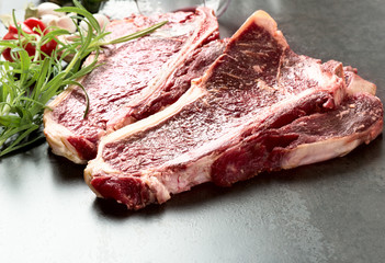 Raw aged steak and seasoning on dark background
