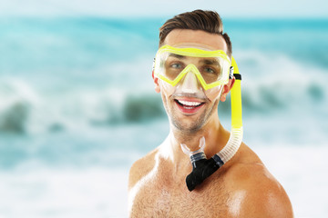 Young man with swimming mask or goggles on blurred sea background