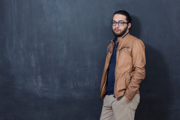 Attractive young man against blackboard.