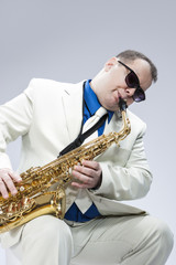 Fototapeta premium Caucasian Mature Male Musician Playing Alto Saxophone and Wearing Sunglasses