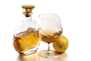 Bottle and snifter brandy with lemon on white background