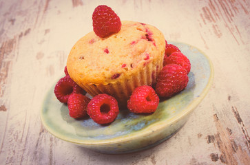 Vintage photo, Fresh baked cupcake with raspberries and fruits on old wooden background, delicious dessert