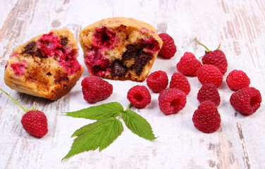 Fresh baked muffins with chocolate and raspberries on wooden background, delicious dessert