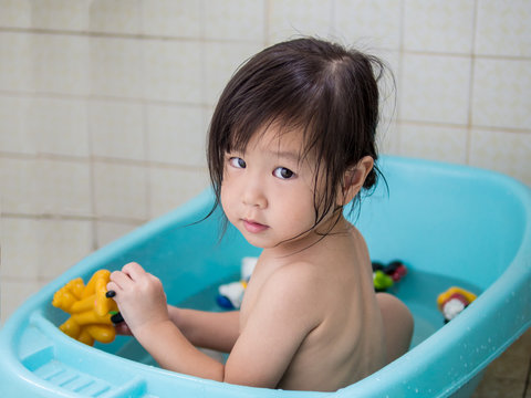 Asian Baby Girl Is Playing In Bath Tub With Toy