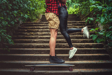 Casual moder young skateboarders couple posing on footway.