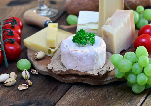 Käseplatte mit Brie, Parmesan, Emmentaler und Gruyere auf Holz mit Trauben und Kirschtomaten