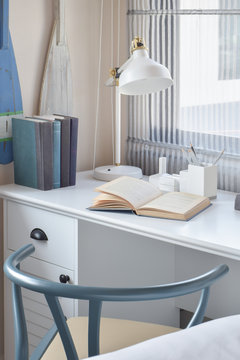 white table with wooden chair books and lamp in modern working area