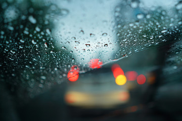 Raindrops on the windshield glass with blurry traffic background