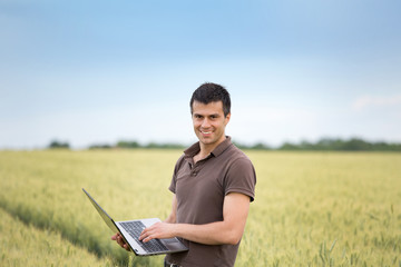 farmer with laptop in wheat field