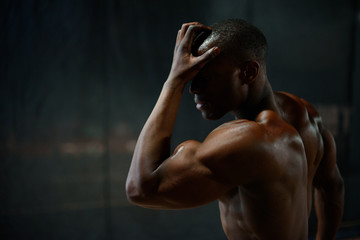 Close-up portrait of handsome african american male body builder with naked torso posing and...