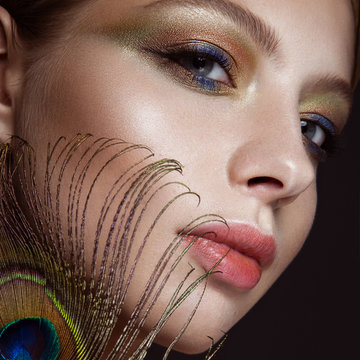 Beautiful girl with bright colored makeup and peacock feather on her face. Beauty. Close-up