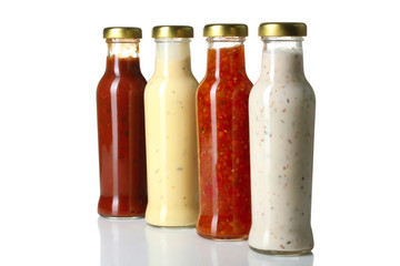 a variety of sauces in glass bottles on a white isolated background