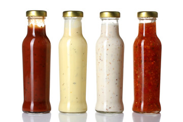 a variety of sauces in glass bottles on a white isolated background