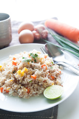A dish of fried rice, carrot and egg on brown fabric, spoon, fol