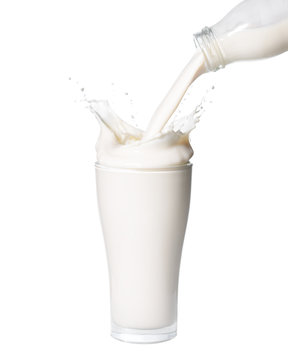 Pouring milk from bottle into glass with splashing., Isolated white background.