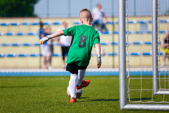 Young boy soccer football goalkeeper kicking soccer ball on a sports field