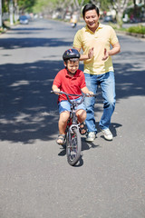 Fototapeta premium Father teaching his son riding a bike