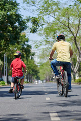 Rear view of father and son enjoying cycling along the road