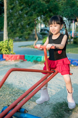 Happy kid, asian baby child playing on a seesaw