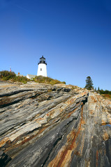 Fototapeta na wymiar lighthouse located on a rocky hill, sunny day. Boulders in the foreground. USA. Maine 