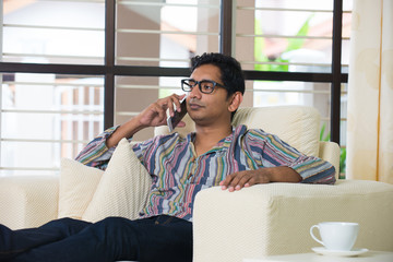 Fototapeta premium casual indian male with phone on sofa looking angry