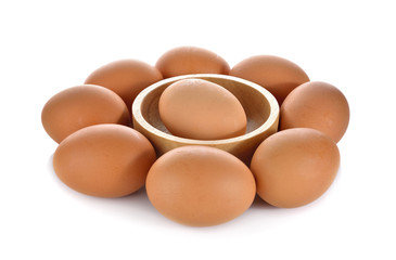 one egg in wooden bowl and others around on white background