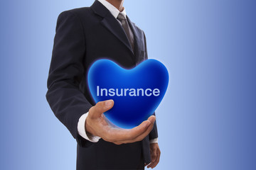 Businessman hand holding blue heart bubble with insulance word 