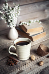 Large Cup of coffee on vintage wooden background. Spring flowers and books.