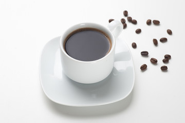 White coffee cup filled with black coffee and beans