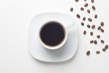 White coffee cup filled with black coffee beans, top view