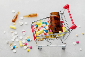 Shopping cart full of pharmaceutical drug and medicine pills on light background