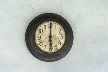 Old antique clock hanging on the wall shows six o'clock.