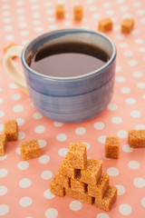 blue cup of tea and lump sugar on pink background