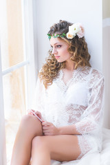 beautiful girl in a white bridal negligee sitting